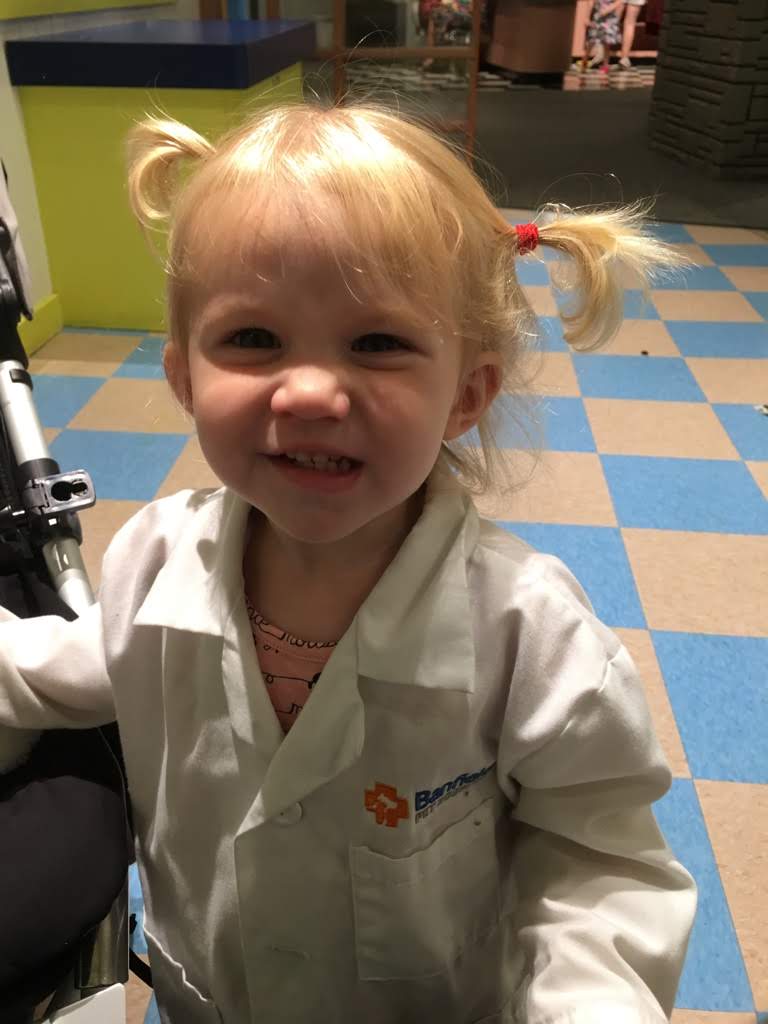 little girl smiling in a dress up vet coat