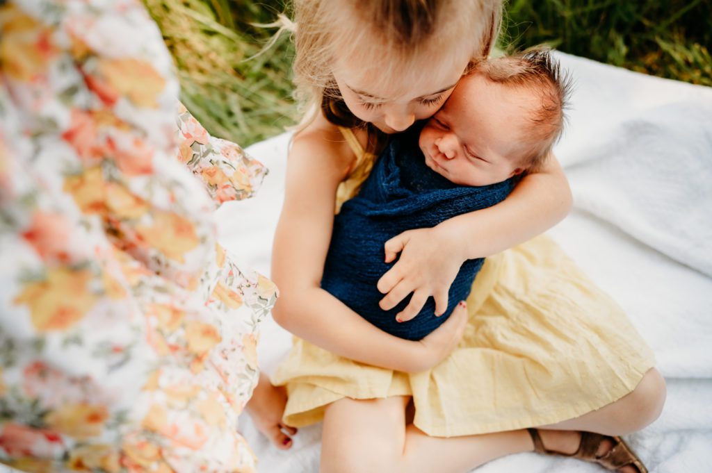 photo of a little girl hugging her newborn brother in a wildflower field outside Cincinnati