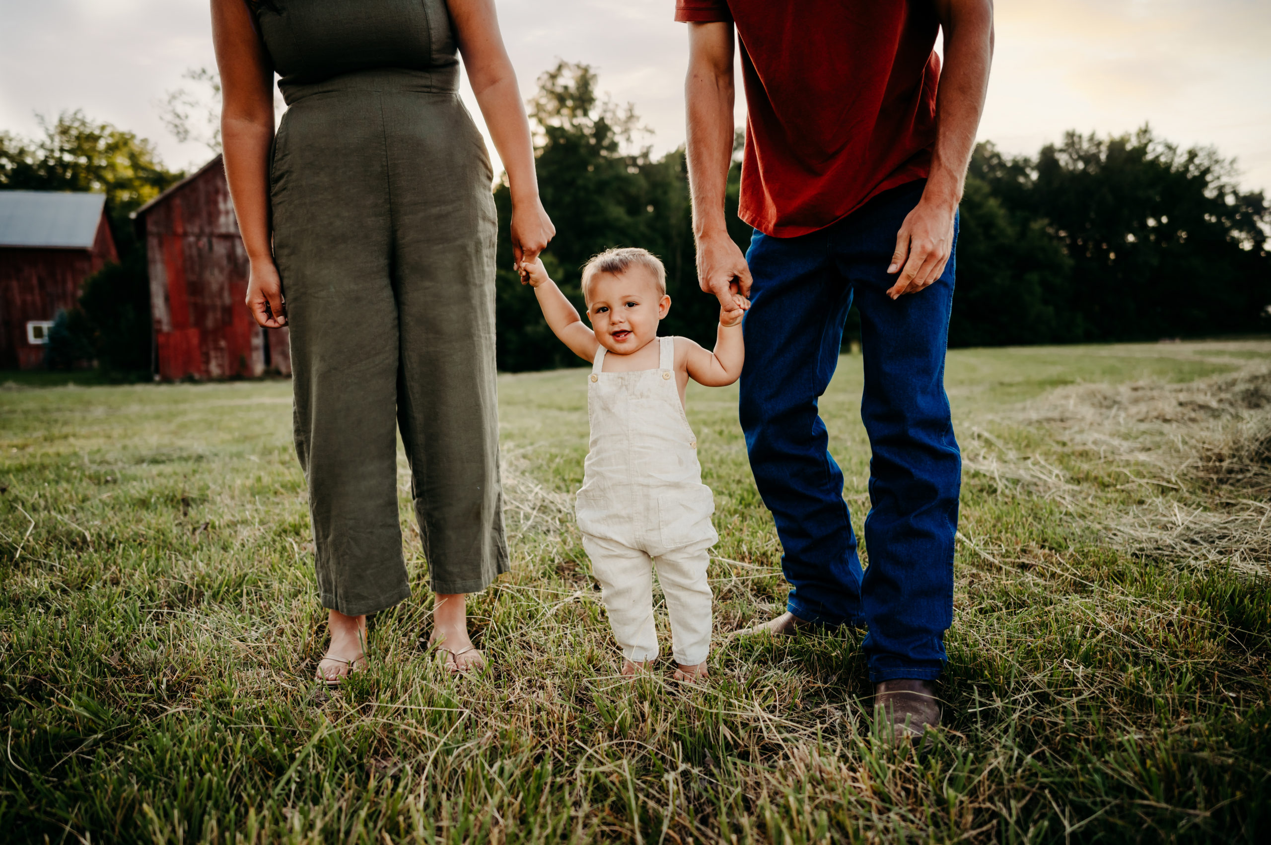 Child holding his parents hands in a field in Cincinnati